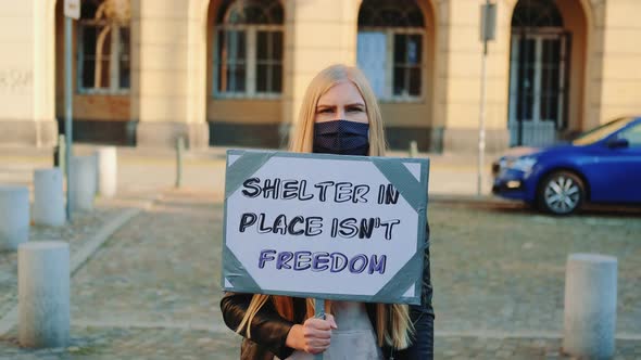 Woman in Mask Protesting That Shelter in Place Does Not Mean Freedom alt