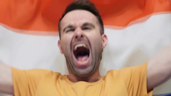 Netherlands Fan Celebrates Holding the Flag of Netherlands alt