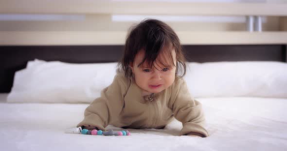 Upset Baby Crying Lying on Her Stomach on the Bed in the Nursery