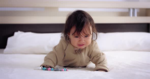 Upset Baby Crying Lying on Her Stomach on the Bed in the Nursery alt