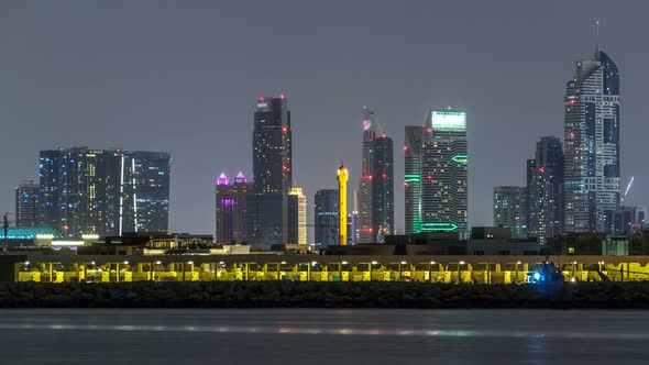 Modern Dubai City Skyline Timelapse at Night with Illuminated Skyscrapers Over Water Surface alt