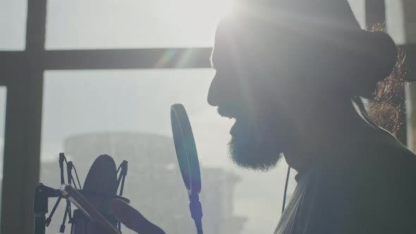 Closeup of the Attractive Bearded Man Singing Into a Microphone in Sun Backlight