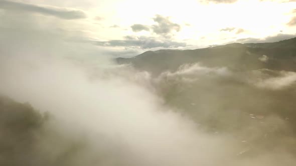 Aerial view flying above lush green tropical rain forest mountain with rain cloud cover during the r alt
