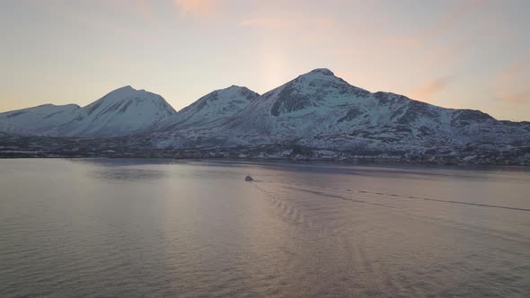 Flying above fjord on Kvaløya, Tromsø. Northern Norway. Following the wake of a fishing boat. 4K dr alt