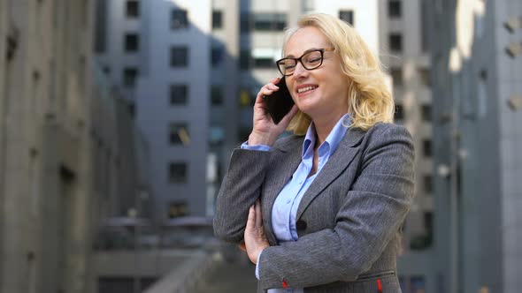 Cheerful Female Manager Talking on Phone Standing Outside, Client Communication alt