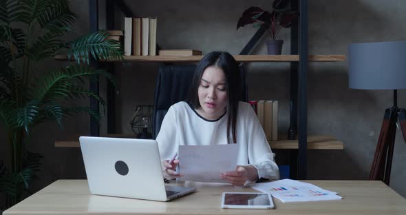 Focused Asian Millennial Woman Studying From Home Online Training Listening to Teacher Taking Notes alt