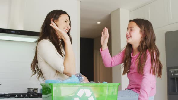 Happy caucasian mother and daughter segregating rubbish, giving high five alt