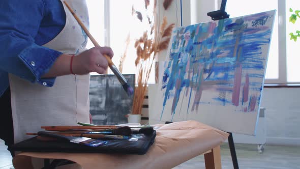 A Woman Paint Artist Taking a Brush and Drawing a Colorful Abstract Painting on a Canvas alt
