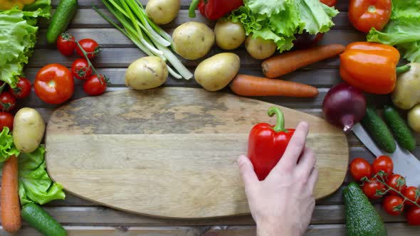 Hands of Male Chef Putting Bell Pepper on Cutting Board alt
