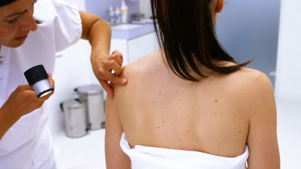 Doctor performing laser hair removal treatment on patient skin alt