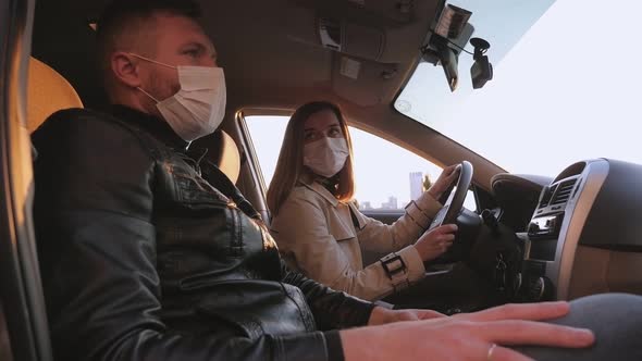 Couple in Medical Masks and Gloves are Sitting in Car alt