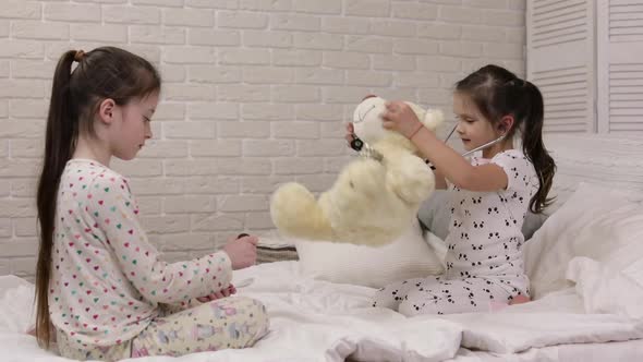 Two Cute Children Girls Playing Doctor with Teddy Bear