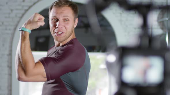 Sportsman Talking and Demonstrating Muscles on Camera alt