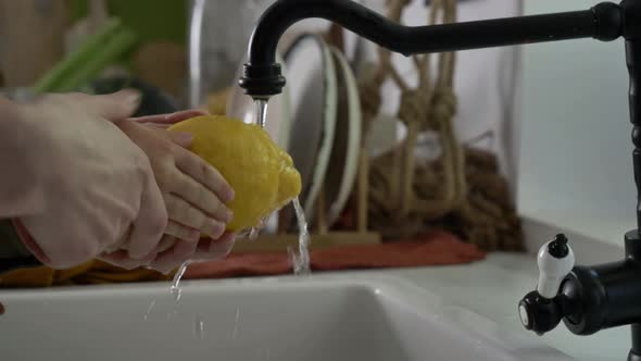 Little boy washing lemon with mother in kitchen alt