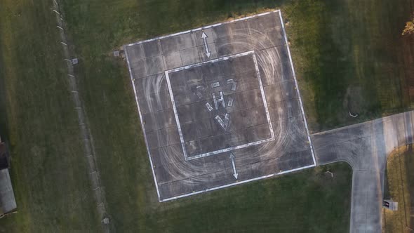 Aerial drone top down circling view of empty heliport for helicopter in green meadow alt