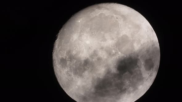 Zoomed in big full Moon is floating on black night sky, dramatic dark clouds passing over - timelaps alt