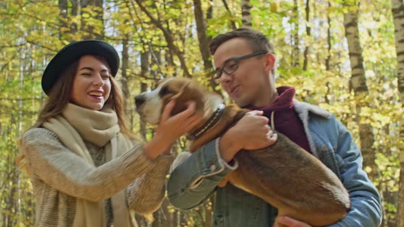 Owners hug their dog in a forest alt