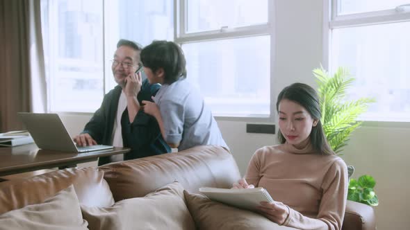 asian dad mom working at home with laptop smarthpone at dinning room alt