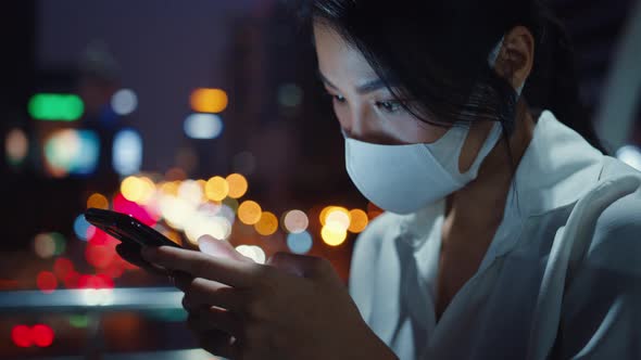 Young Asia businesswoman in fashion clothes wearing face mask using smart phone typing text message