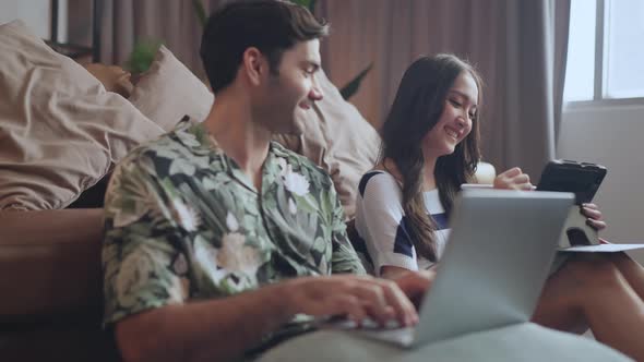 home isolate quarantine,asian and caucasian marry couple sit relax using laptop and tablet