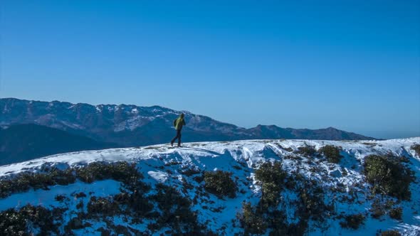 A man walks runs on top of snow covered mountains alt