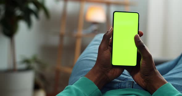 Guy in Casual Clothes Lying on Couch and Touching Smatphone Mock Up Display, African Man Browsing alt