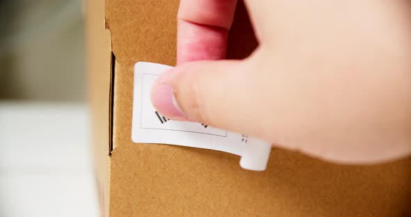 Hands applying MADE IN KOREA  flag label on a shipping cardboard box with products. Close up shot wi alt