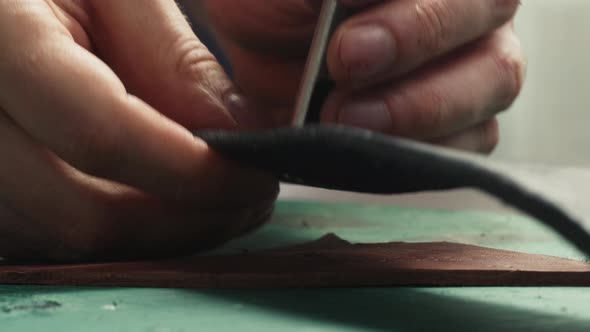 Man Hands Making Hole in Leather Belt with Professional Tools Closeup alt