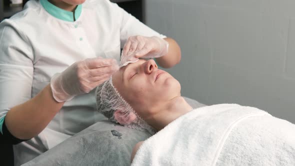 The Cosmetologist Cleanses the Man's Face with Cotton Pads with Gel