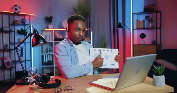 Worker in Headset Sitting in front of Computer During Video Conference with Coworkers alt