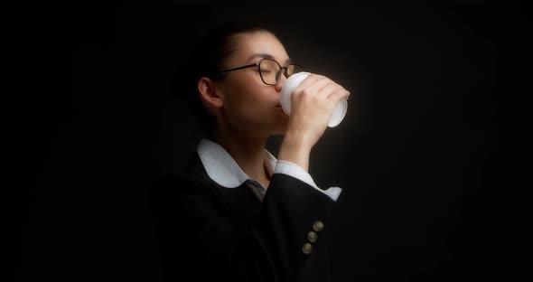 Brunette in Glasses and Office Clothes Drinks Coffee From a White Paper Cup