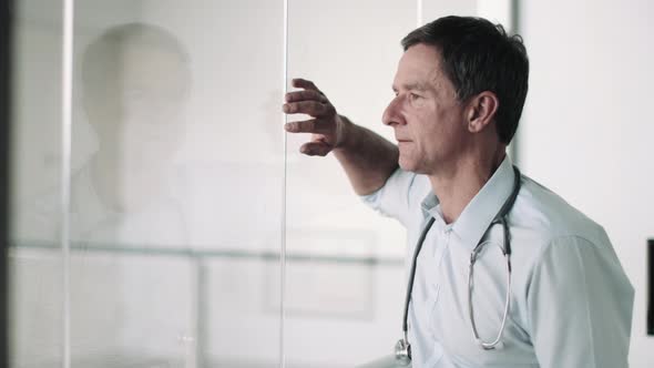 Mature Adult Male Doctor in Hospital looking out of window