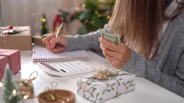Girl Counting US Dollar Bills Using Calculator and Writing Expenses alt