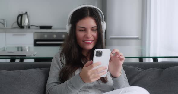 A Lovely Smiling Millennial Teen Girl is Talking to Someone with a Video Chat While Sitting in the alt