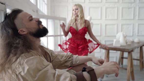 Artist is Sitting on Floor of His Workshop Waiting Muse and Inspiration Lady in Red is Dancing alt