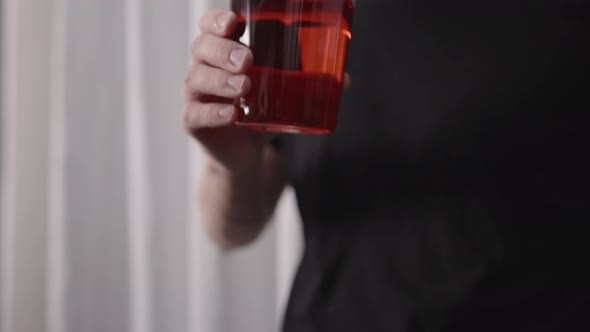 Slow Motion Man Drinking Red Drink From Tumbler Glass Near Window alt