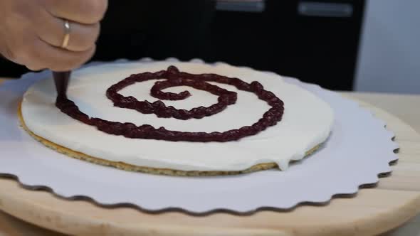 Applying Berry Juice to the First Thin Sponge Cake with Cream for a Large Cake