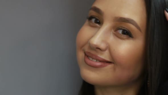 Brunette european woman looking at camera while standing in the office on gray background alt