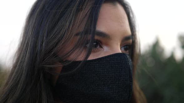 A beautiful young hispanic woman wearing a reusable cloth respiratory face mask to prevent infection alt