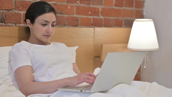 Young Indian Woman Working on Laptop in Bed alt