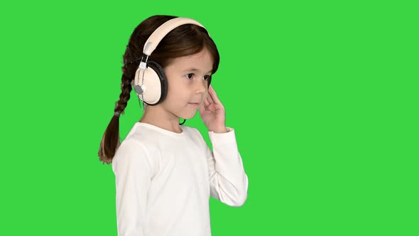 Cute Girl Dressed in White Holding Headphones with One Hand and Nodding Her Head To the Music While alt