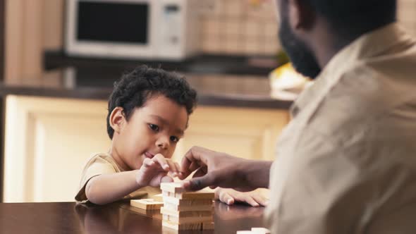 African American man teaching his son to put Jenga blocks