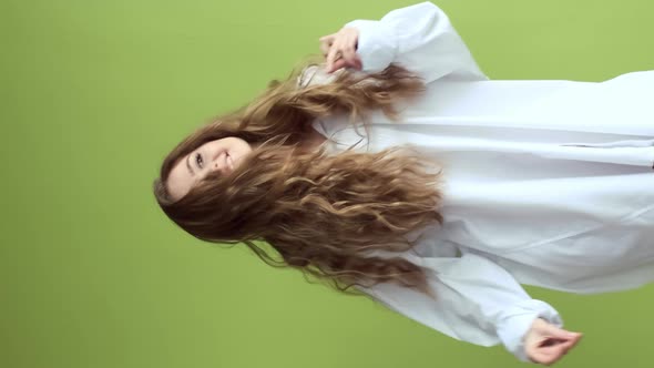 Girl With Long Hair Dancing On Background Of Light Green Wall. alt