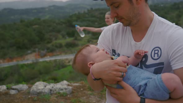 Dad Rocks Baby Girl in Arms Against Mom with Bottle of Water alt