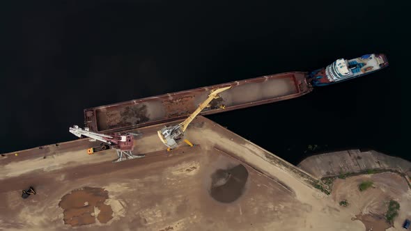 Large Harbor Cranes Onshore at the Quay Unload a River Gravel Barge Onto a Large Pile alt