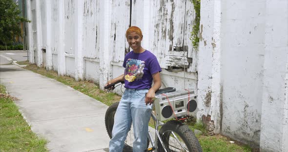 This video is about a Young attractive female resting on bike and listening to boom box. This video alt