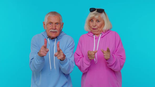 Senior Man Woman Grandparents Pointing Around with Finger Gun Gesture Shooting Killing Hand Pistol alt