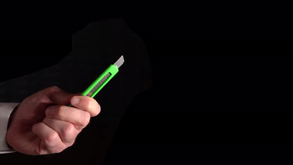 Stationery Knife In Hand On Black Background