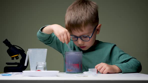 Boy in Glasses Doing Experiment. Young Scientist Mixing Up Licquid for Experiments. Preschooler