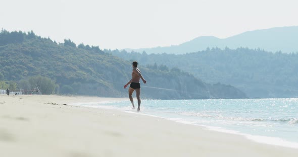 The Handsome Man with a Perfect Athletic Body in Swimming Trunks Having Fun on a Deserted Beach in alt